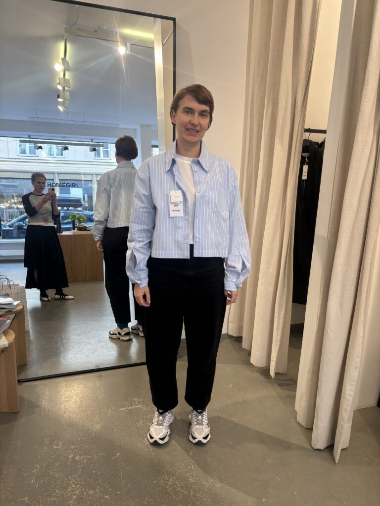 Kundin probiert beim Personal Shopping in München ein modernes Outfit mit gestreifter Bluse, dunkler Hose und Sneakern an, während Personal Stylistin Heide von STYLEFINDS den Look fotografiert.